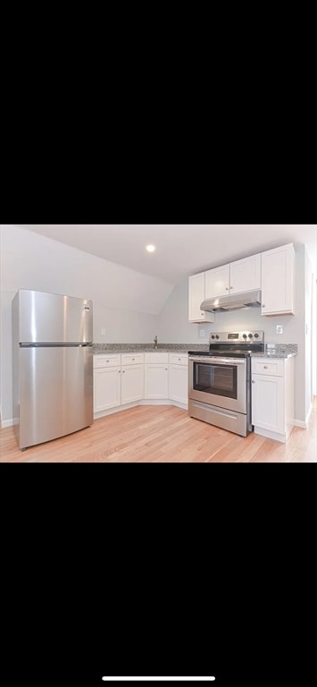 kitchen featuring white cabinets, stainless steel appliances, light hardwood / wood-style floors, and vaulted ceiling