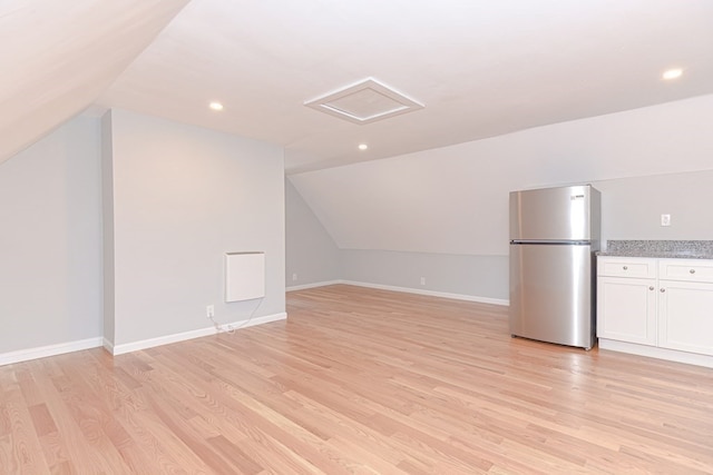 additional living space featuring light wood-type flooring and lofted ceiling