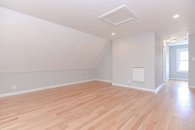 additional living space with light wood-type flooring and vaulted ceiling