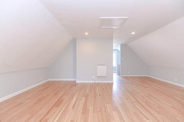 additional living space with light hardwood / wood-style flooring and vaulted ceiling