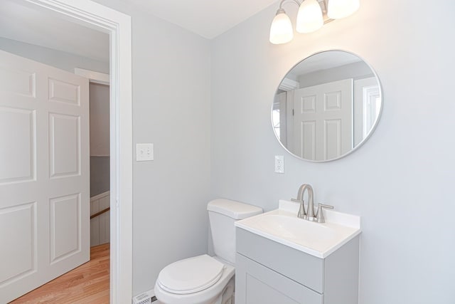 bathroom featuring wood-type flooring, toilet, and vanity