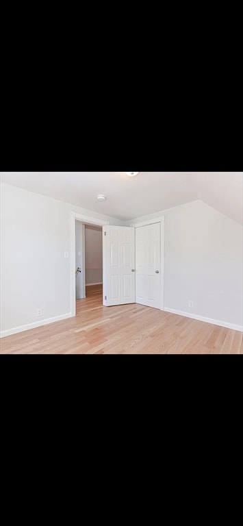 unfurnished room featuring vaulted ceiling and light hardwood / wood-style flooring