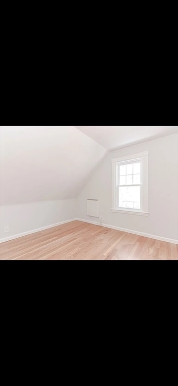 bonus room featuring light wood-type flooring and vaulted ceiling