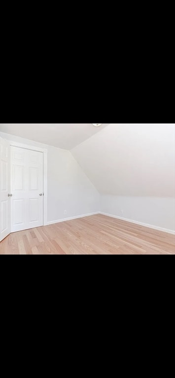 additional living space with light hardwood / wood-style floors and lofted ceiling