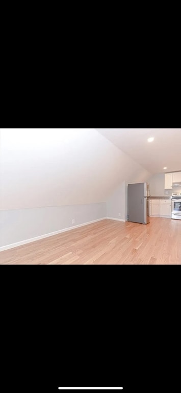 additional living space with lofted ceiling and light hardwood / wood-style floors