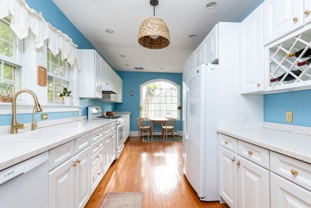 136 Walnut St, Braintree, MA 02184 - kitchen with white appliances, light countertops, white cabinetry, light wood-style flooring, and under cabinet range hood