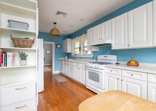 136 Walnut St, Braintree, MA 02184 - kitchen with white gas range oven, under cabinet range hood, light countertops, white cabinets, and light wood-type flooring