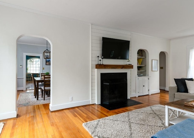 136 Walnut St, Braintree, MA 02184 - living area featuring arched walkways, light wood-style flooring, ornamental molding, and a large fireplace