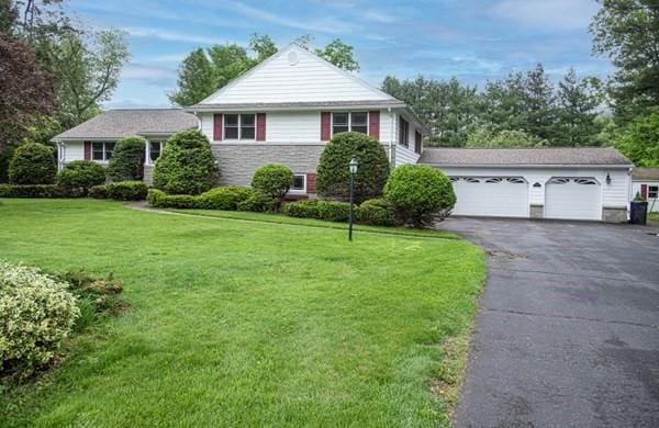 view of front of property featuring a front lawn, stone siding, and driveway