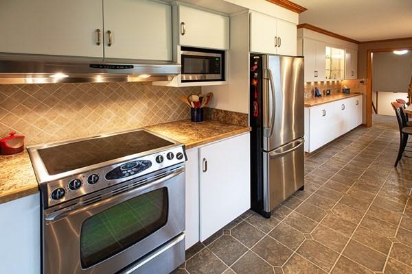kitchen with appliances with stainless steel finishes, under cabinet range hood, decorative backsplash, white cabinetry, and light countertops