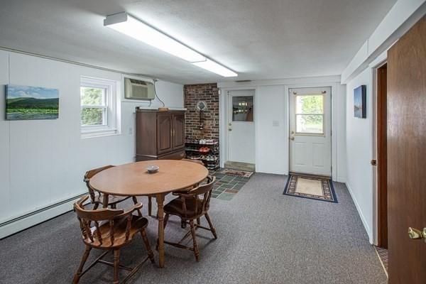 dining area with healthy amount of natural light, a wall unit AC, and carpet floors
