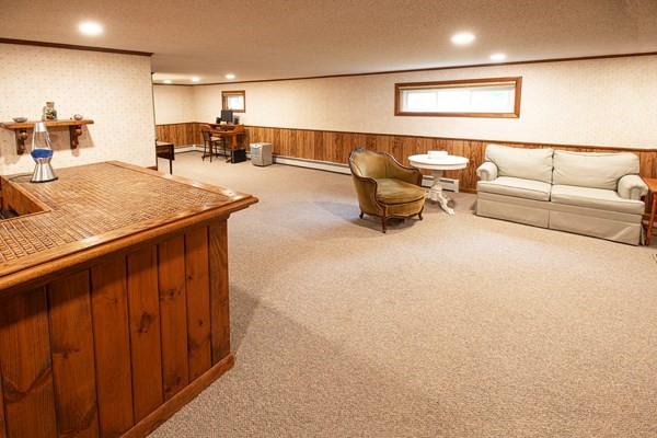 carpeted living area featuring a wainscoted wall, baseboard heating, recessed lighting, and wood walls