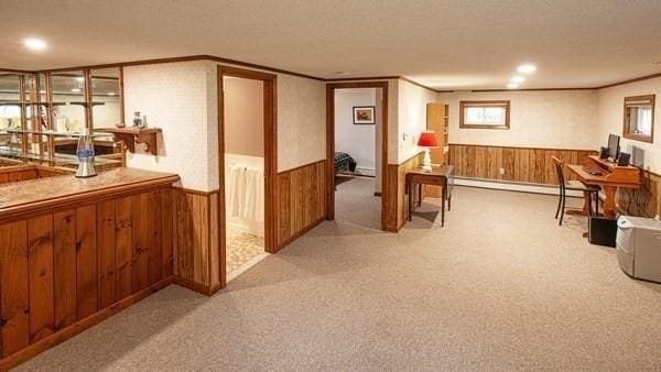 home office featuring a wainscoted wall, a baseboard radiator, wooden walls, carpet flooring, and a textured ceiling