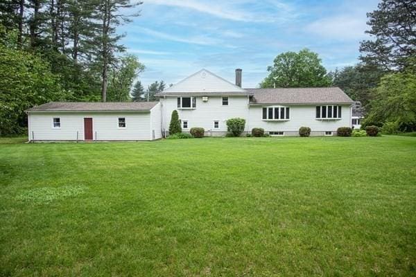 rear view of house with a lawn and a chimney