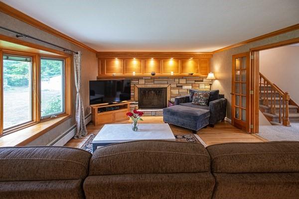 living area featuring ornamental molding, stairs, light wood-style floors, and baseboard heating