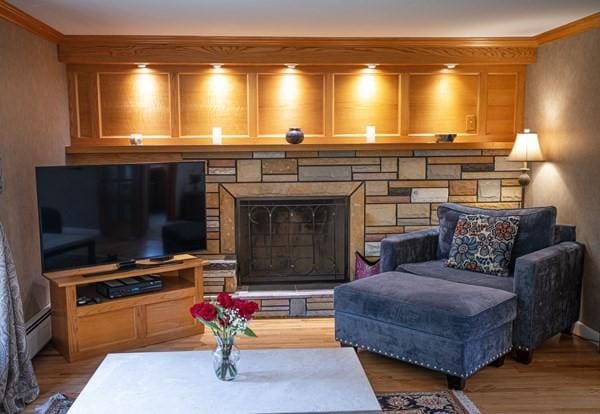 living area with crown molding, wood finished floors, and a baseboard heating unit