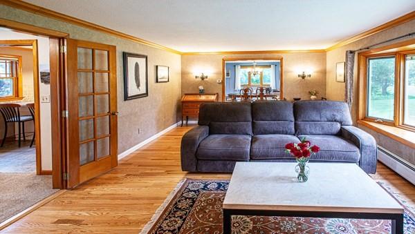 living area with light wood-style floors, french doors, crown molding, baseboards, and a baseboard heating unit