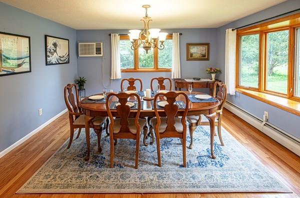 dining room with a baseboard heating unit, a chandelier, plenty of natural light, and a wall mounted AC