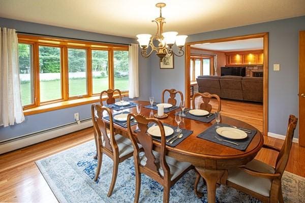 dining space featuring a chandelier, wood finished floors, a baseboard heating unit, and baseboards