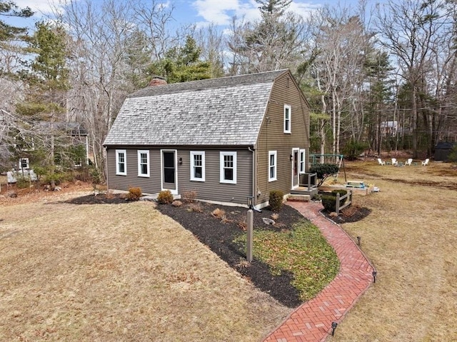 dutch colonial featuring a front yard, a chimney, and a gambrel roof