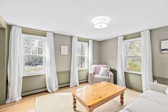 sitting room featuring a baseboard radiator and light wood finished floors