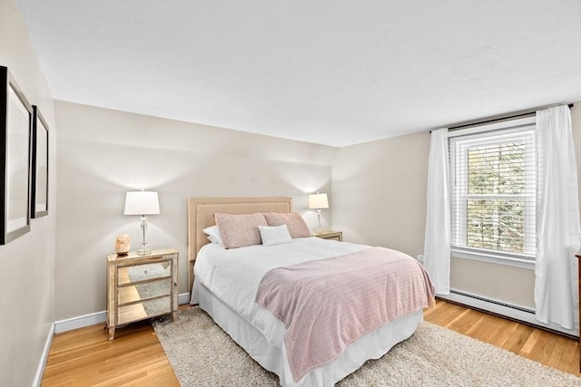 bedroom with light wood finished floors, baseboards, and baseboard heating