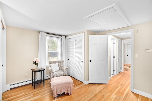 living area featuring a baseboard radiator, light wood-style floors, attic access, and baseboards