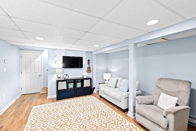 living area featuring baseboards, a drop ceiling, a baseboard radiator, wood finished floors, and recessed lighting