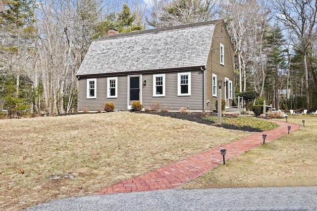 dutch colonial featuring a shingled roof, a chimney, a front yard, and a gambrel roof