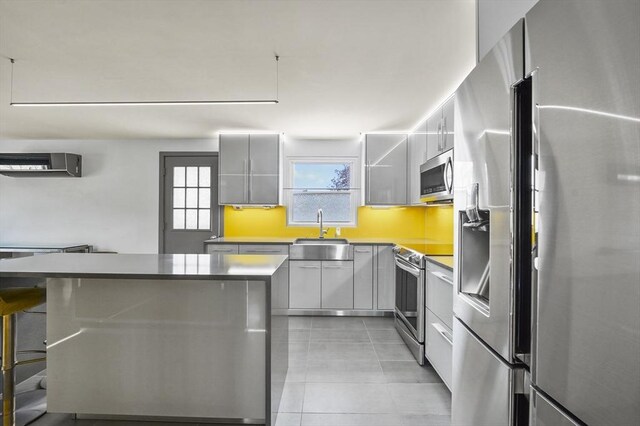 kitchen featuring appliances with stainless steel finishes, modern cabinets, a wall mounted air conditioner, a sink, and light tile patterned flooring