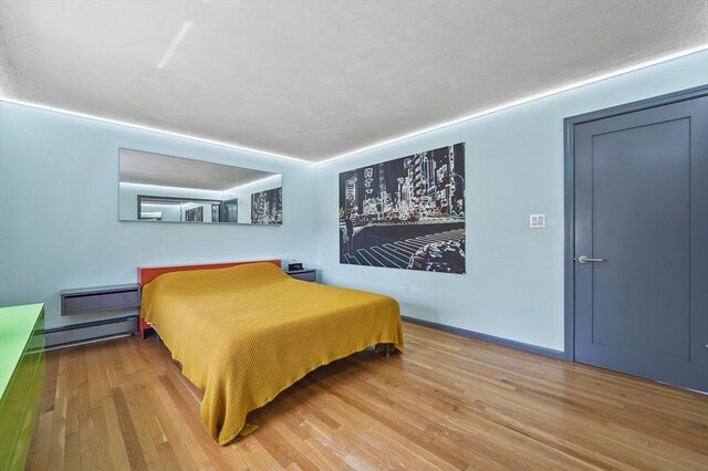 bedroom featuring a baseboard heating unit and wood finished floors