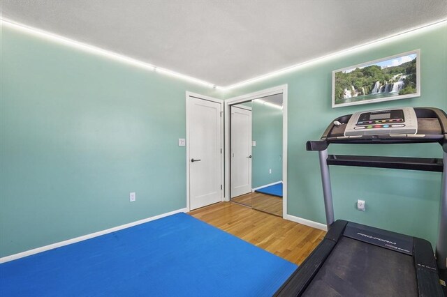workout room featuring baseboards and wood finished floors