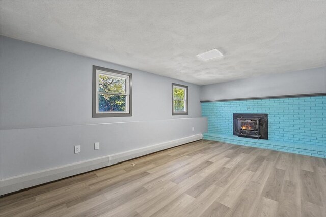 unfurnished living room featuring baseboards, a textured ceiling, and wood finished floors