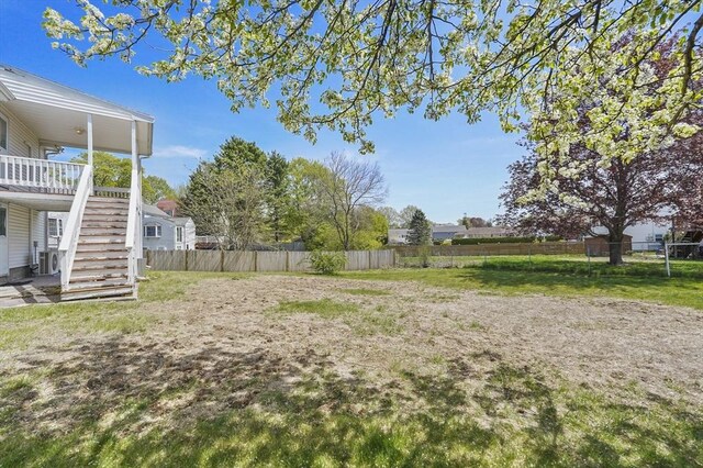 view of yard with fence, ac unit, and stairs