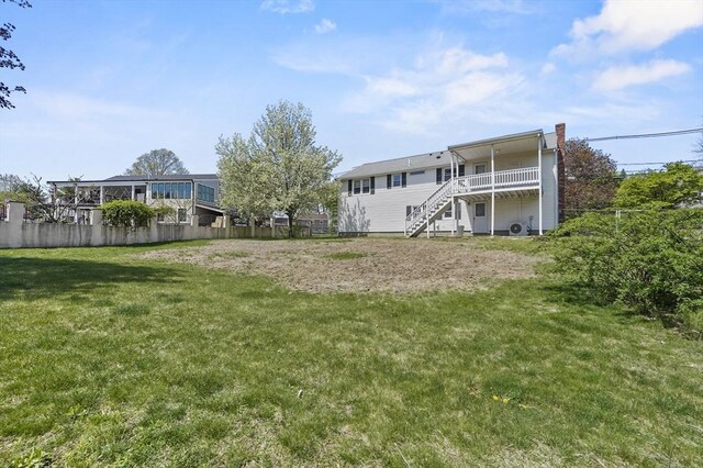 rear view of property with a chimney, a lawn, a deck, stairway, and fence