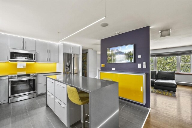 kitchen with modern cabinets, a center island, dark tile patterned flooring, gray cabinetry, and stainless steel appliances