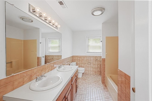 24 Highcrest Park Unit 24, Webster, MA 01570 - bathroom featuring toilet, double vanity, tile walls, wainscoting, and tile patterned floors