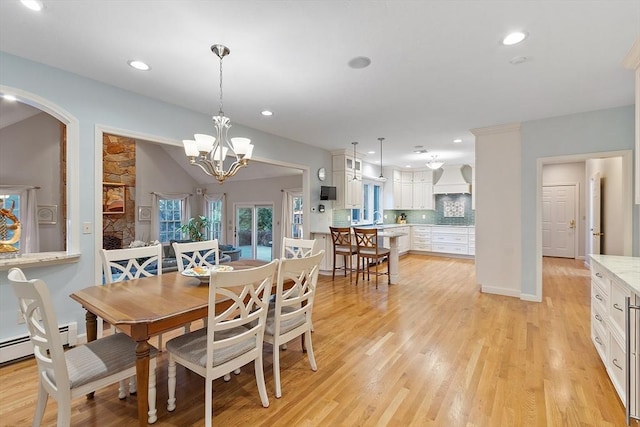 dining space with a notable chandelier, a baseboard heating unit, sink, light hardwood / wood-style flooring, and lofted ceiling