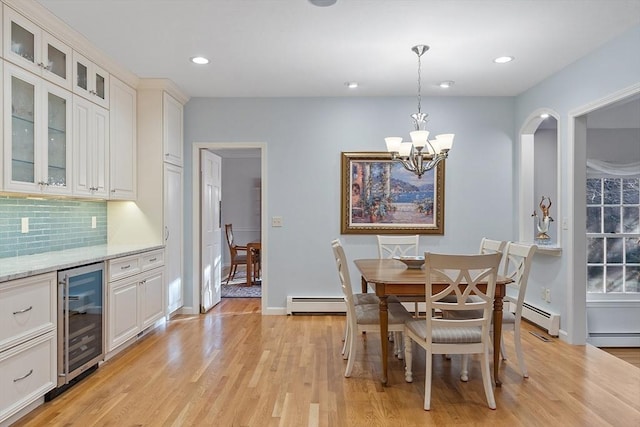 dining room featuring light wood-type flooring, a baseboard radiator, a chandelier, and wine cooler