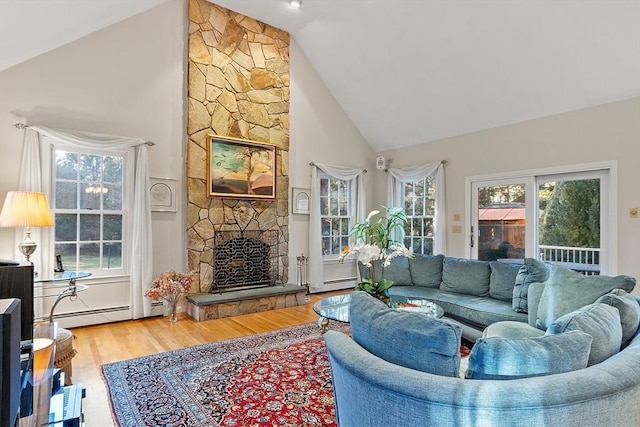 living room with hardwood / wood-style flooring, high vaulted ceiling, baseboard heating, and a stone fireplace