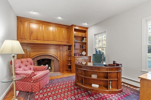 office space featuring a baseboard heating unit, hardwood / wood-style flooring, and a fireplace