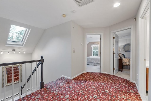 corridor featuring light colored carpet and lofted ceiling with skylight