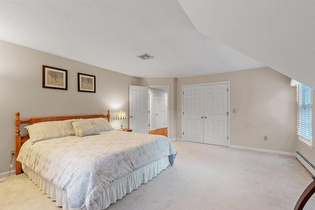 carpeted bedroom with a baseboard heating unit and a closet