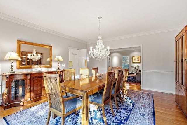 dining space featuring crown molding, an inviting chandelier, and light hardwood / wood-style flooring