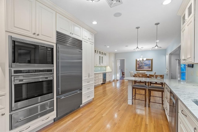 kitchen featuring white cabinets, built in appliances, and light stone counters