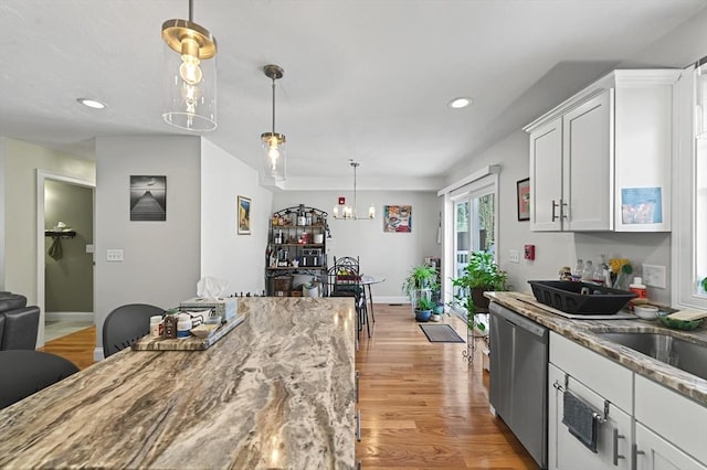 kitchen featuring hanging light fixtures, dishwasher, light stone countertops, light hardwood / wood-style floors, and white cabinets