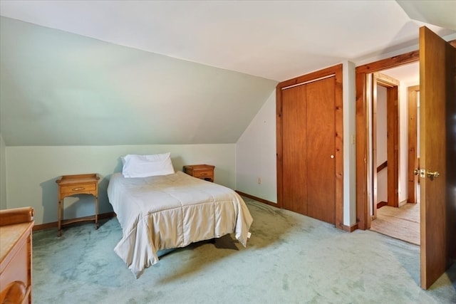 carpeted bedroom with a closet and vaulted ceiling