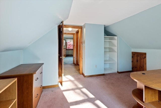 additional living space featuring vaulted ceiling and light colored carpet