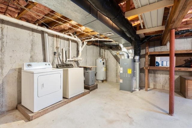 basement featuring electric water heater, independent washer and dryer, and heating unit