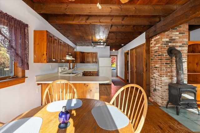 dining space with beamed ceiling, wood ceiling, a wood stove, and dark hardwood / wood-style floors